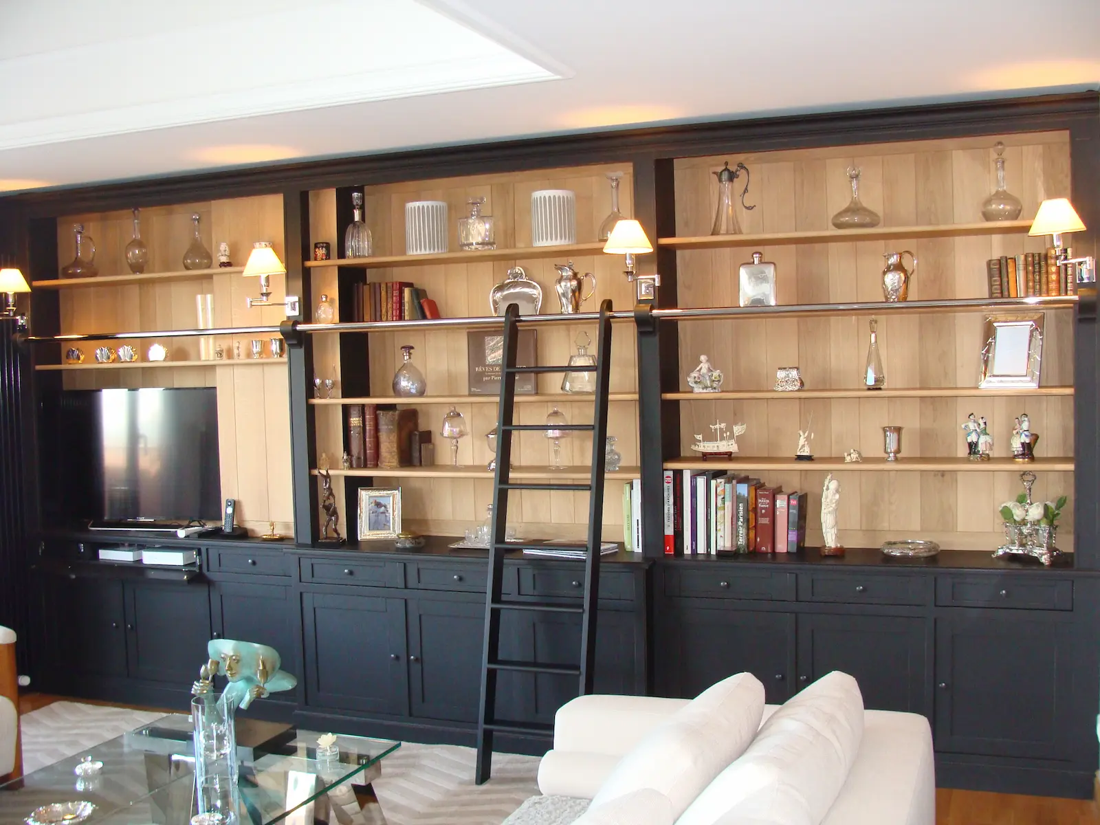 Bibliothèque murale sur mesure en bois avec échelle intégrée, laqué noir et fond en bois vernis, réalisée par un menuisier ébéniste à Sens dans l’Yonne